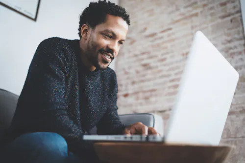Man on couch smiling at laptop