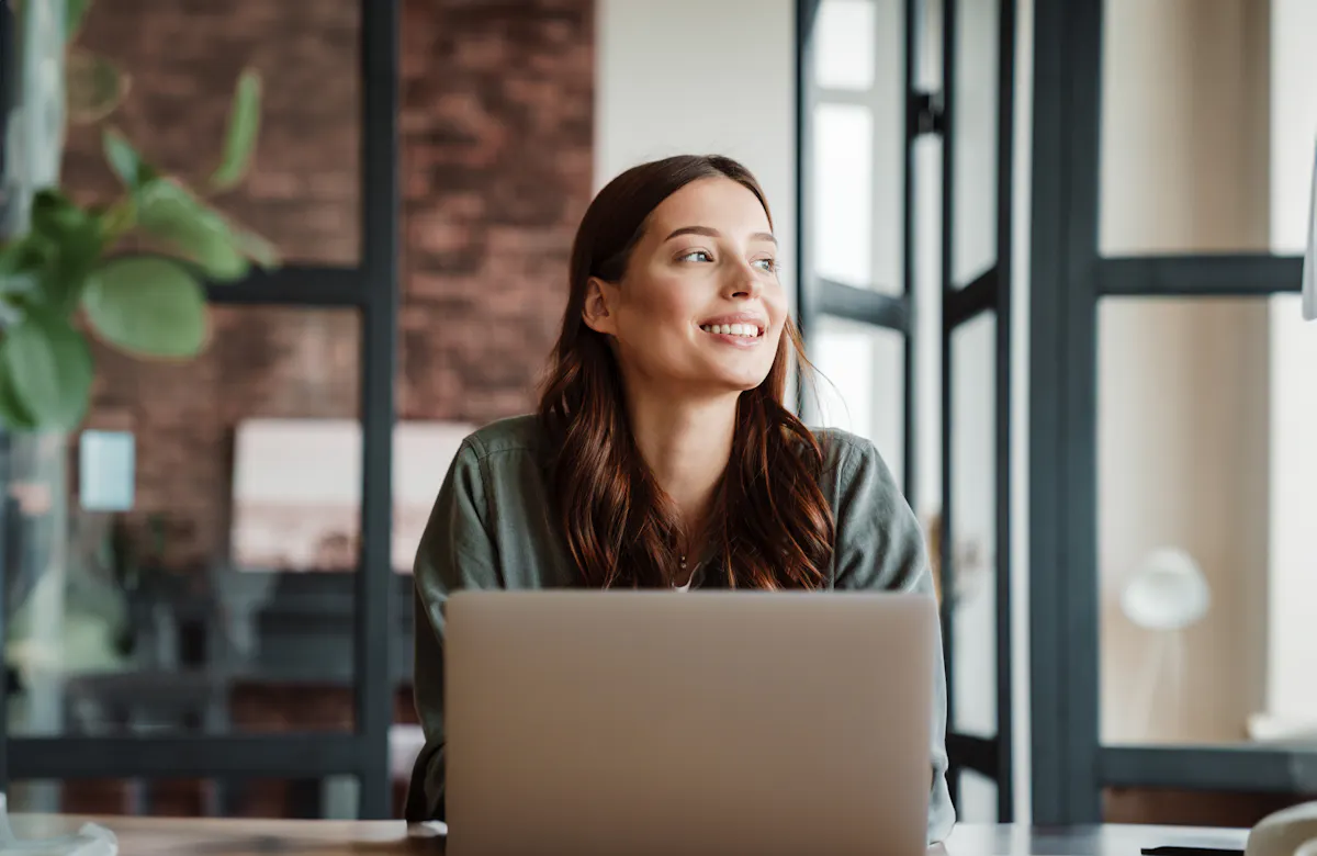 Smiling woman working with laptop while sitting at table